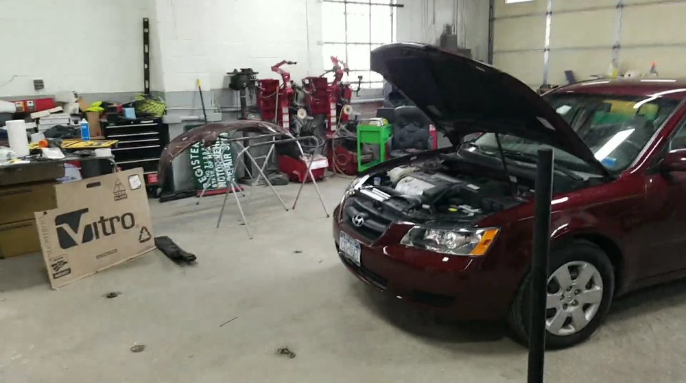 Inside the shop: a red sedan with its hood open